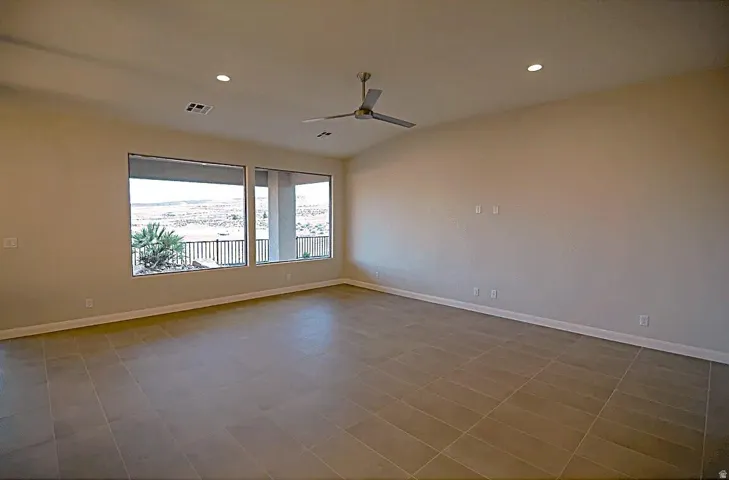 Spacious room with large windows, tile flooring, recessed lighting, a ceiling fan, and a neutral color palette