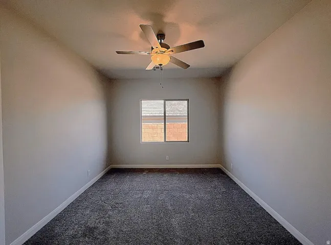 Neutral-toned room featuring a single window with blinds and a ceiling fan