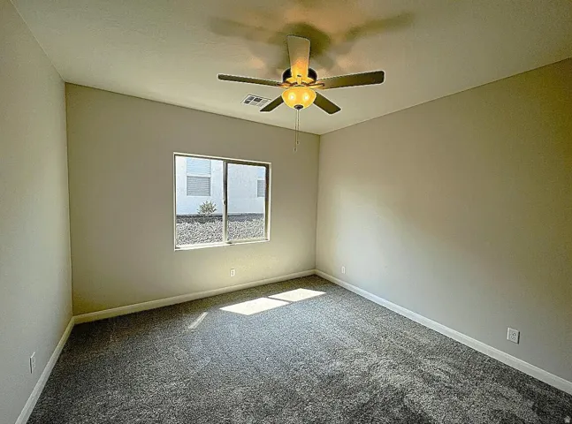 Interior room featuring neutral-toned walls, gray carpeting, and a white-framed window