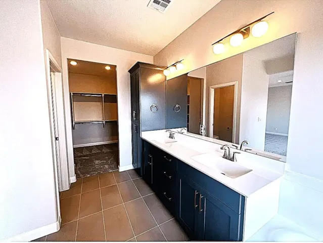 Bathroom featuring a dual vanity with undermount sinks and dark blue cabinetry