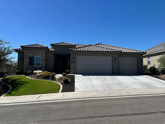 Contemporary stucco exterior featuring stone accents, a tile roof, and an integrated two-car garage