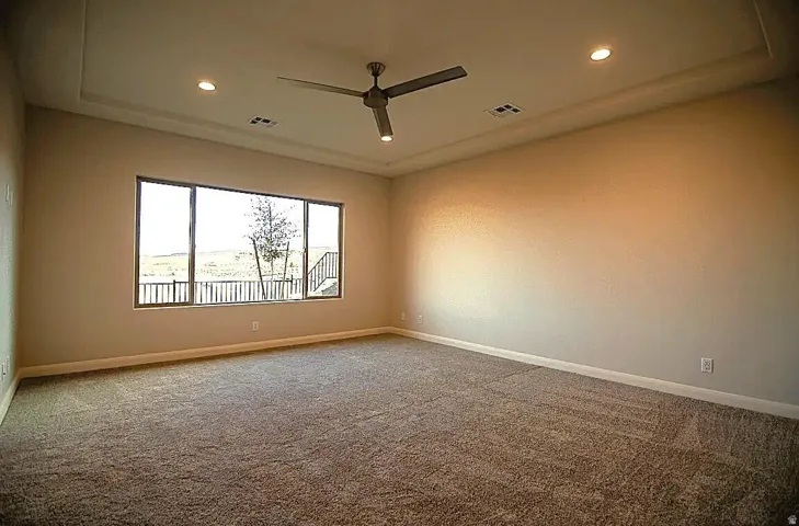 Spacious room featuring broadloom carpeting and a tray ceiling with recessed lighting