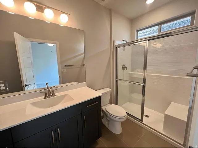 Contemporary bathroom featuring a dark wood-finish vanity with a white countertop and undermount sink, a large mirror, and a glass-enclosed shower with subway tile and an integrated bench