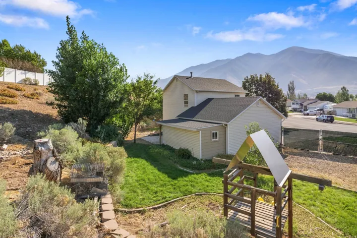 Spacious backyard featuring a manicured lawn, established landscaping, and a wooden playset