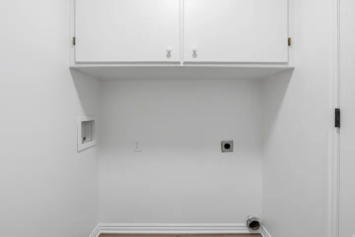 Dedicated laundry area featuring white cabinetry, washer hookups, dryer vent, and electrical outlet