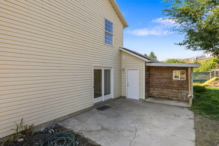 Spacious concrete patio with direct access to the home via sliding glass doors and a white entry door