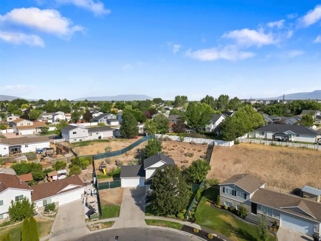 Expansive residential lot featuring a sloped terrain and partial fencing, surrounded by mature trees and established homes