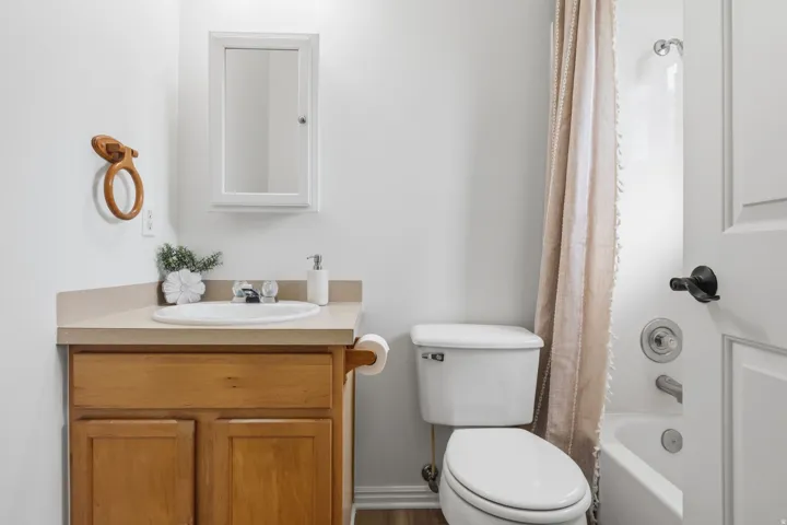 Bathroom vanity with wood cabinetry, an integrated sink, and a light-toned countertop