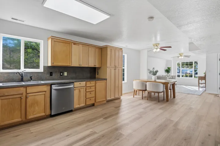 Kitchen featuring wood cabinetry, stainless steel dishwasher, dual basin sink, and a large window