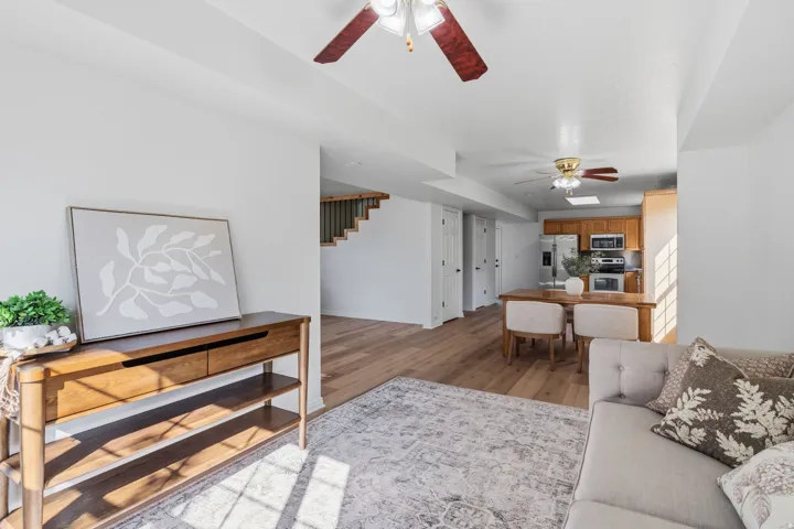 Open concept living space featuring wood-finish flooring, a ceiling fan, and white walls