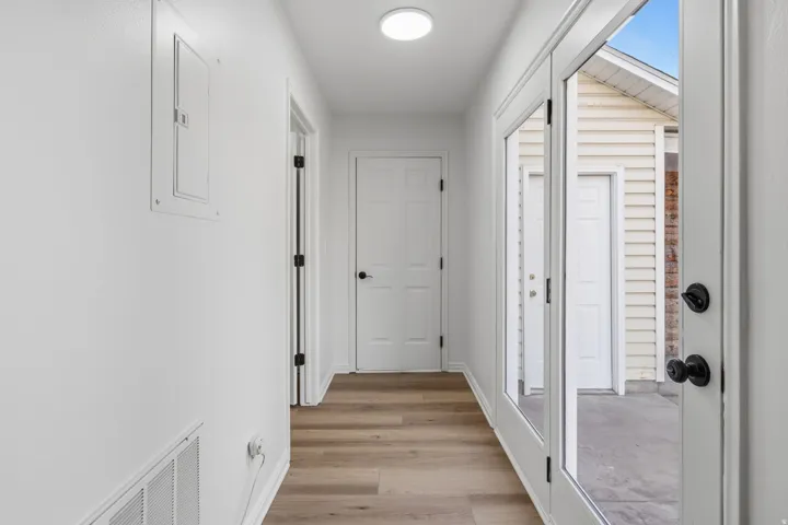 Hallway featuring wood-finish flooring, white walls, and a contemporary flush-mount ceiling light