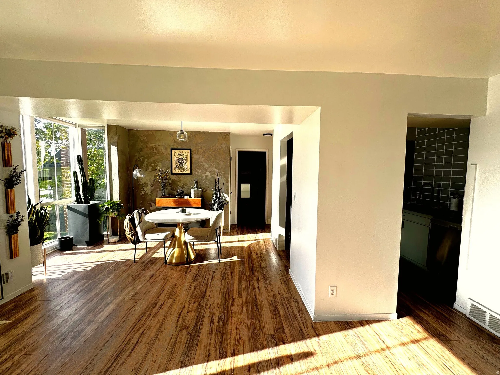 Open-concept living space featuring wood-finish flooring, a prominent bay window, and a textured accent wall
