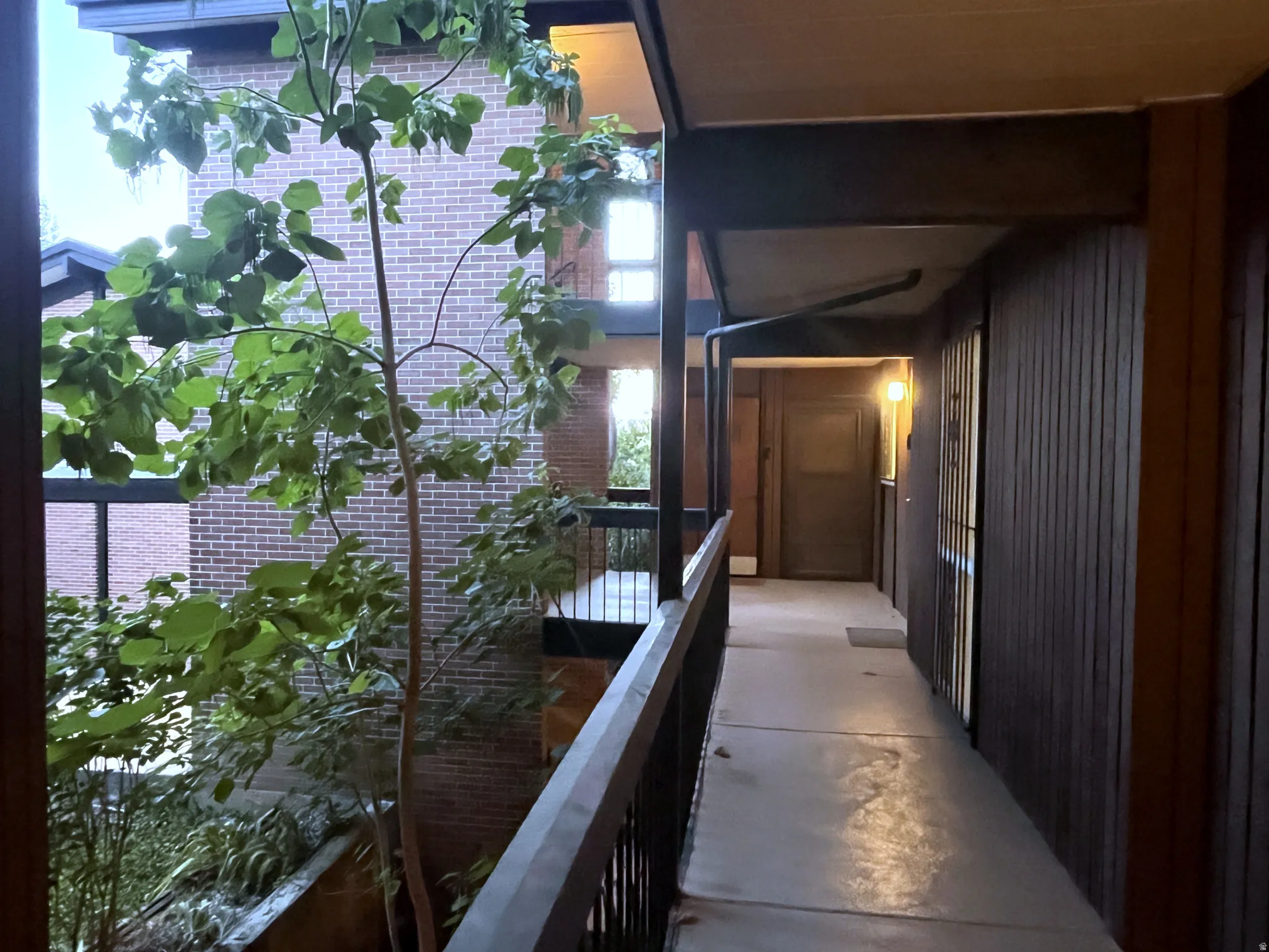 Exterior corridor featuring vertical wood paneling, a concrete walkway, and a dark metal railing
