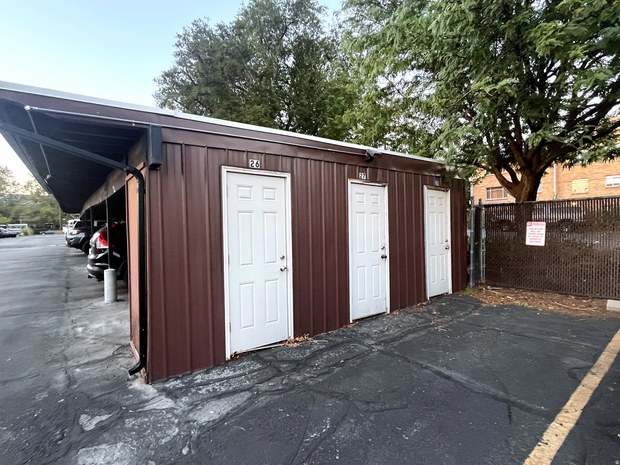 Utility building featuring corrugated metal siding in rich brown tones, paired with three white six-panel doors for accessible entry