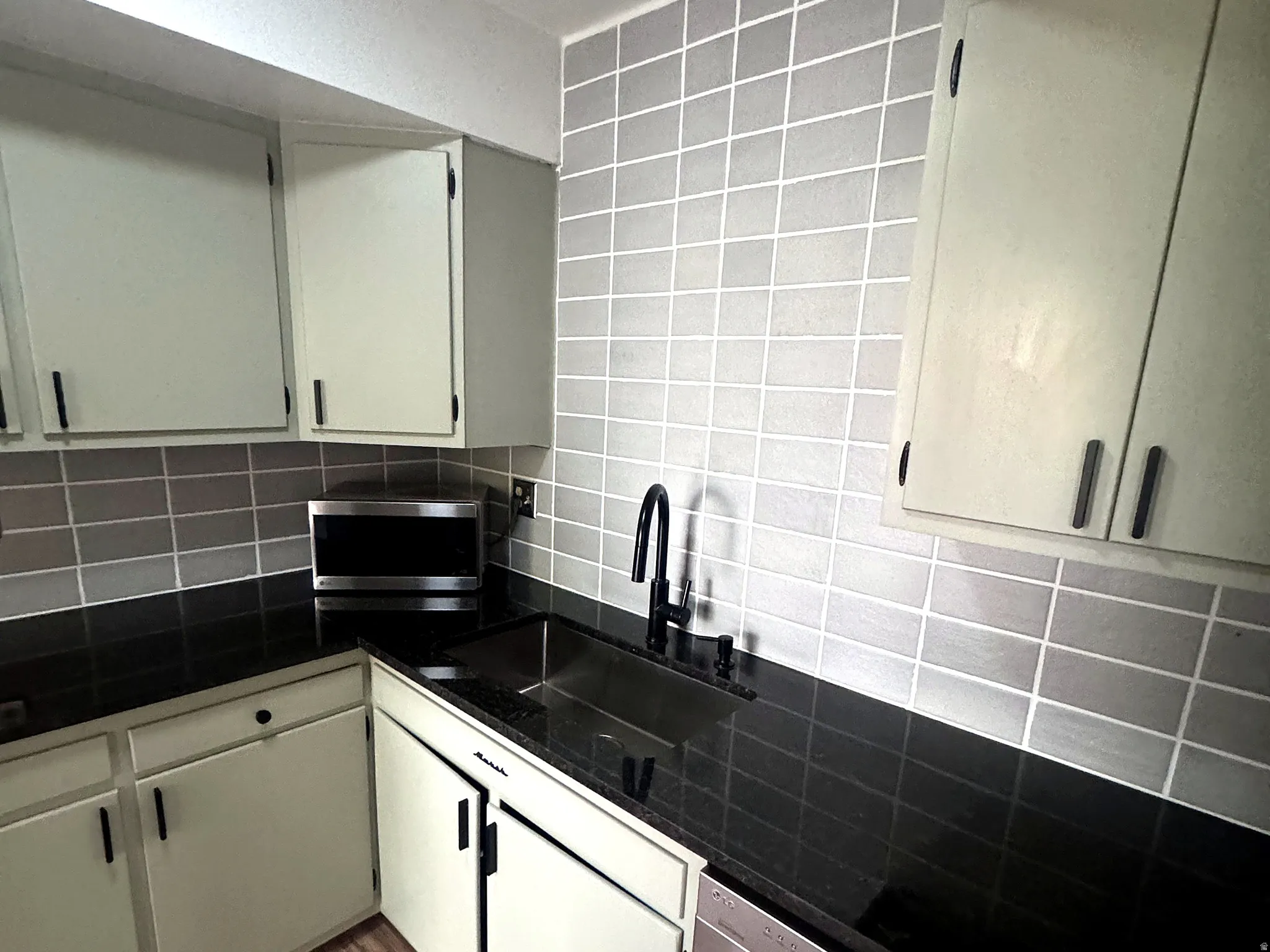 Kitchen featuring light-toned cabinetry with dark hardware, dark countertops, a dark sink, and a black gooseneck faucet
