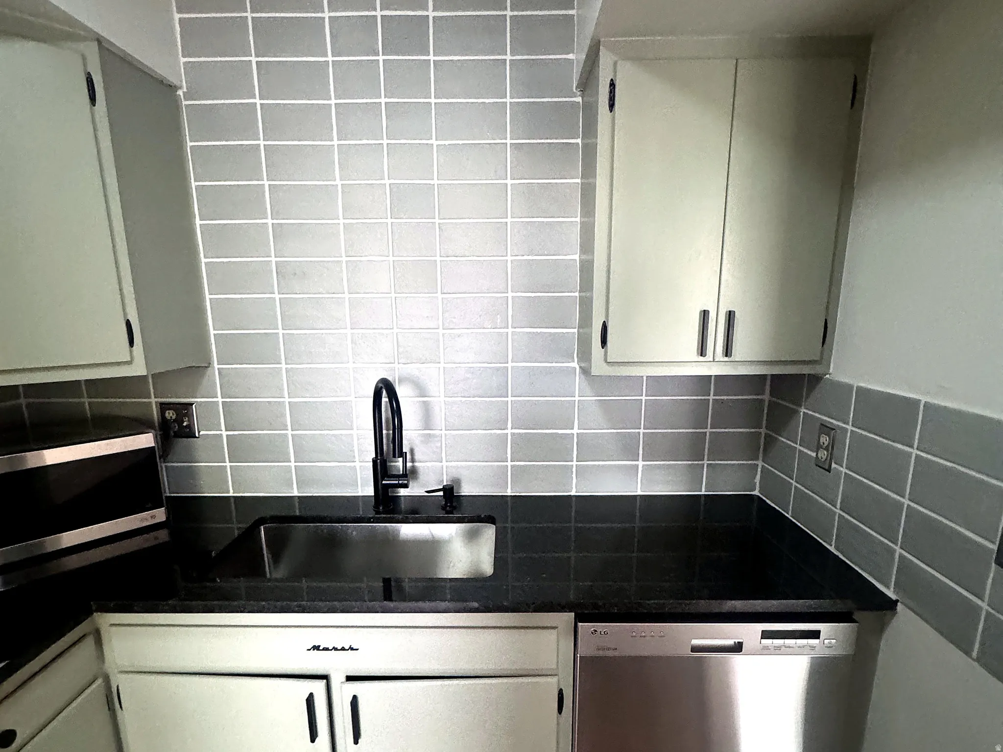 Kitchen area featuring light gray upper cabinetry and a dark countertop