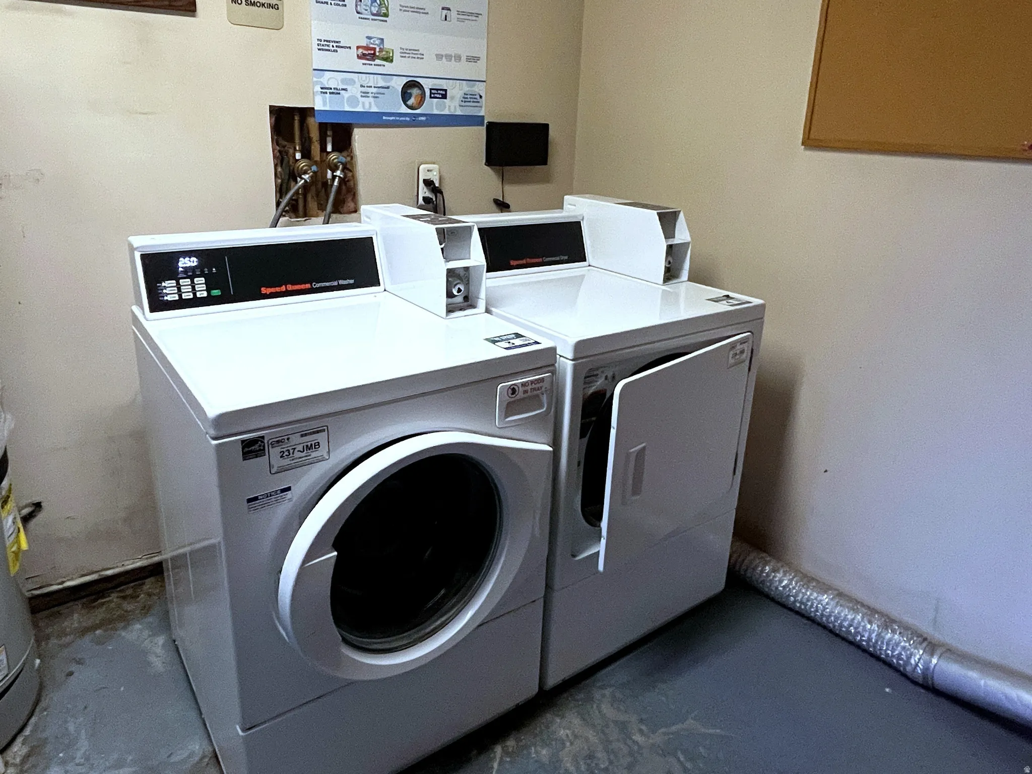 Laundry area featuring stacked white washer and dryer units, a water heater, and exposed overhead ductwork