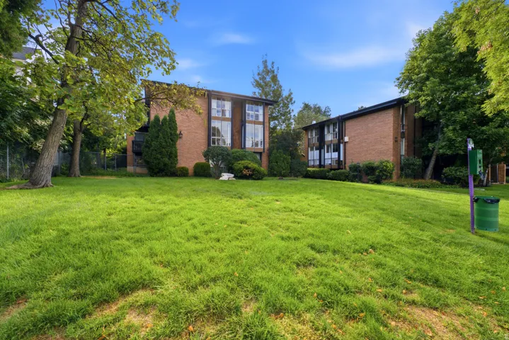 Expansive green lawn with mature trees and brick buildings featuring multiple windows and balconies