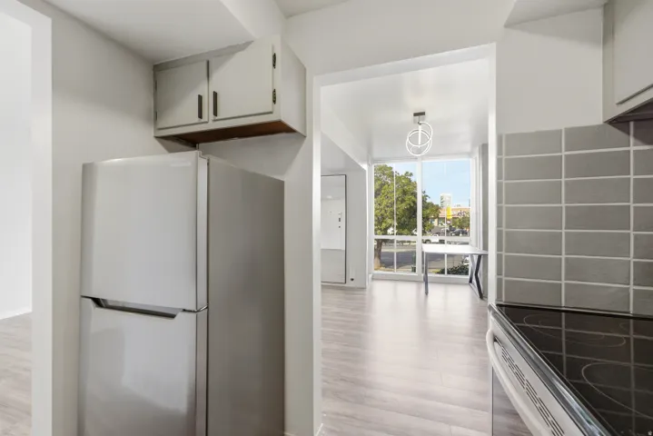 Kitchen area featuring wood-finish flooring, stainless steel refrigerator, and grey tile backsplash