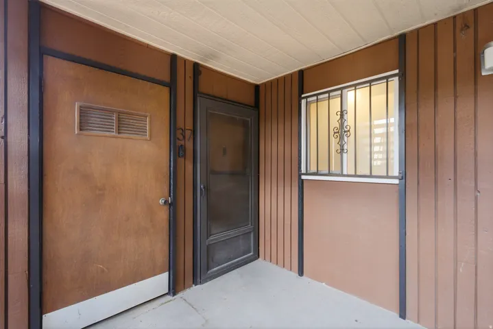 Entryway featuring a wood-panel accent wall, concrete flooring, and a window with decorative security bars