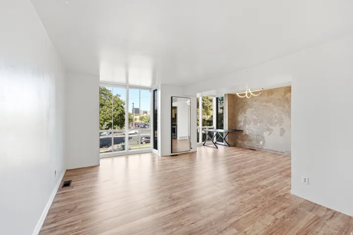 Expansive windows, wood-finish flooring, and a distinct accent wall with a modern light fixture