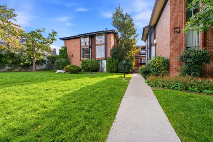 Brick-clad exterior with large windows, surrounded by a manicured lawn and established landscaping