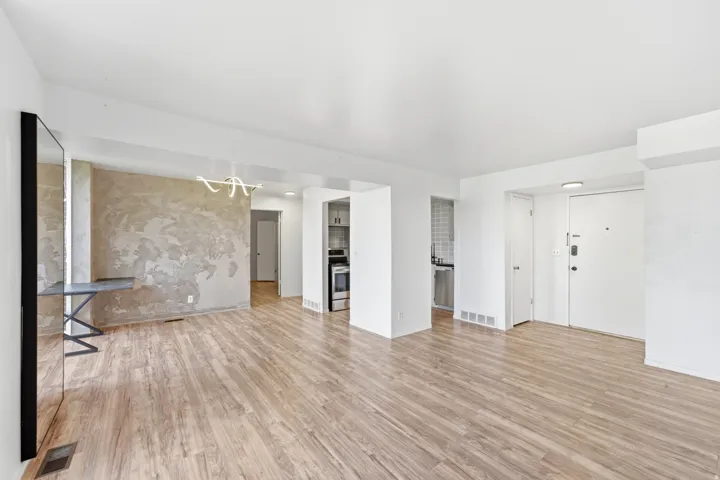 Wood-finish flooring throughout, modern decorative lighting, and a textured accent wall