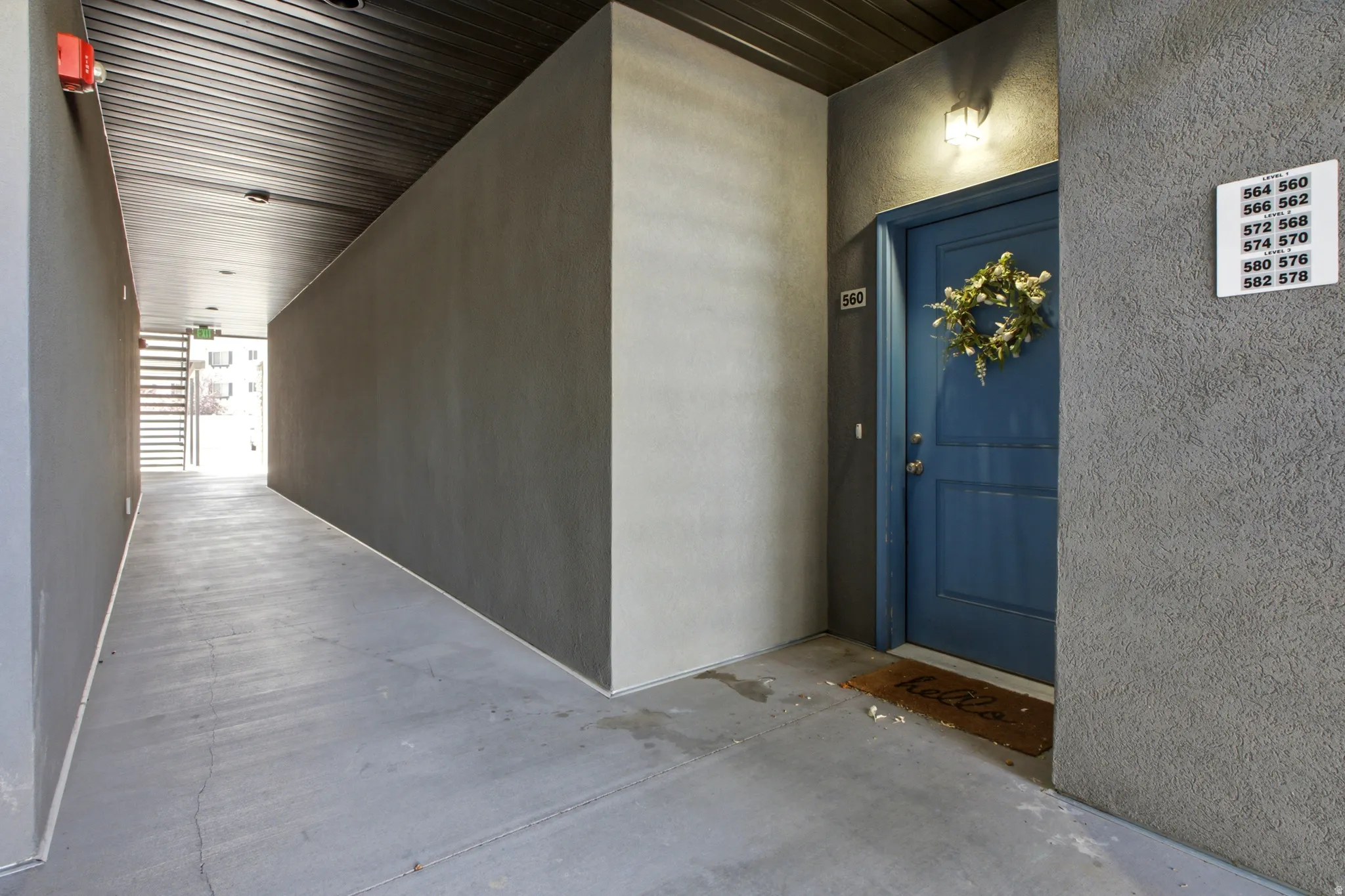 Corridor featuring concrete flooring, textured wall finishes, and a dark paneled ceiling