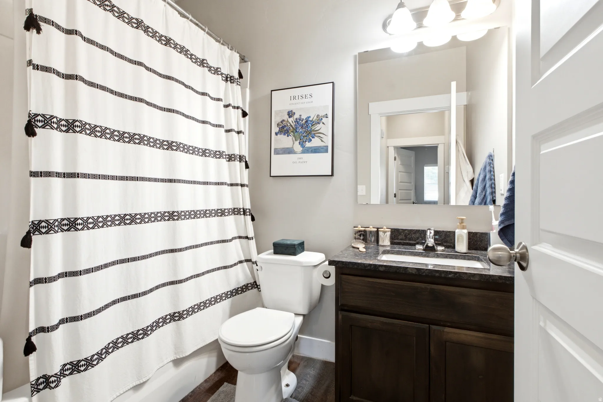 Full bathroom featuring a dark wood-finish vanity with a dark countertop, an undermount sink, and a chrome faucet