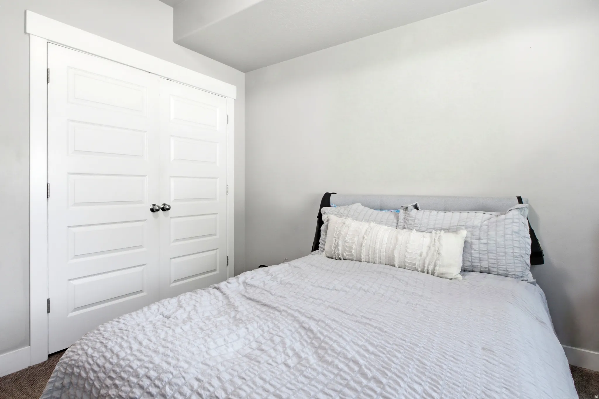 Bedroom featuring light gray wall paint, crisp white trim, and a built-in closet with paneled bifold doors