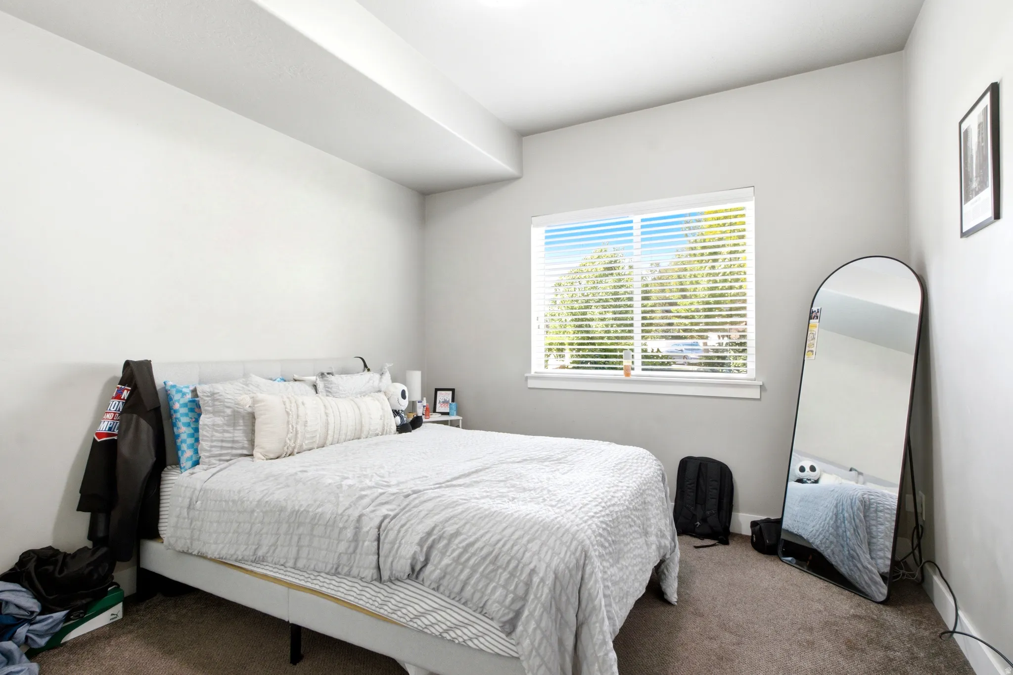 Bedroom featuring neutral-toned walls, a single window with blinds, and dark carpet flooring