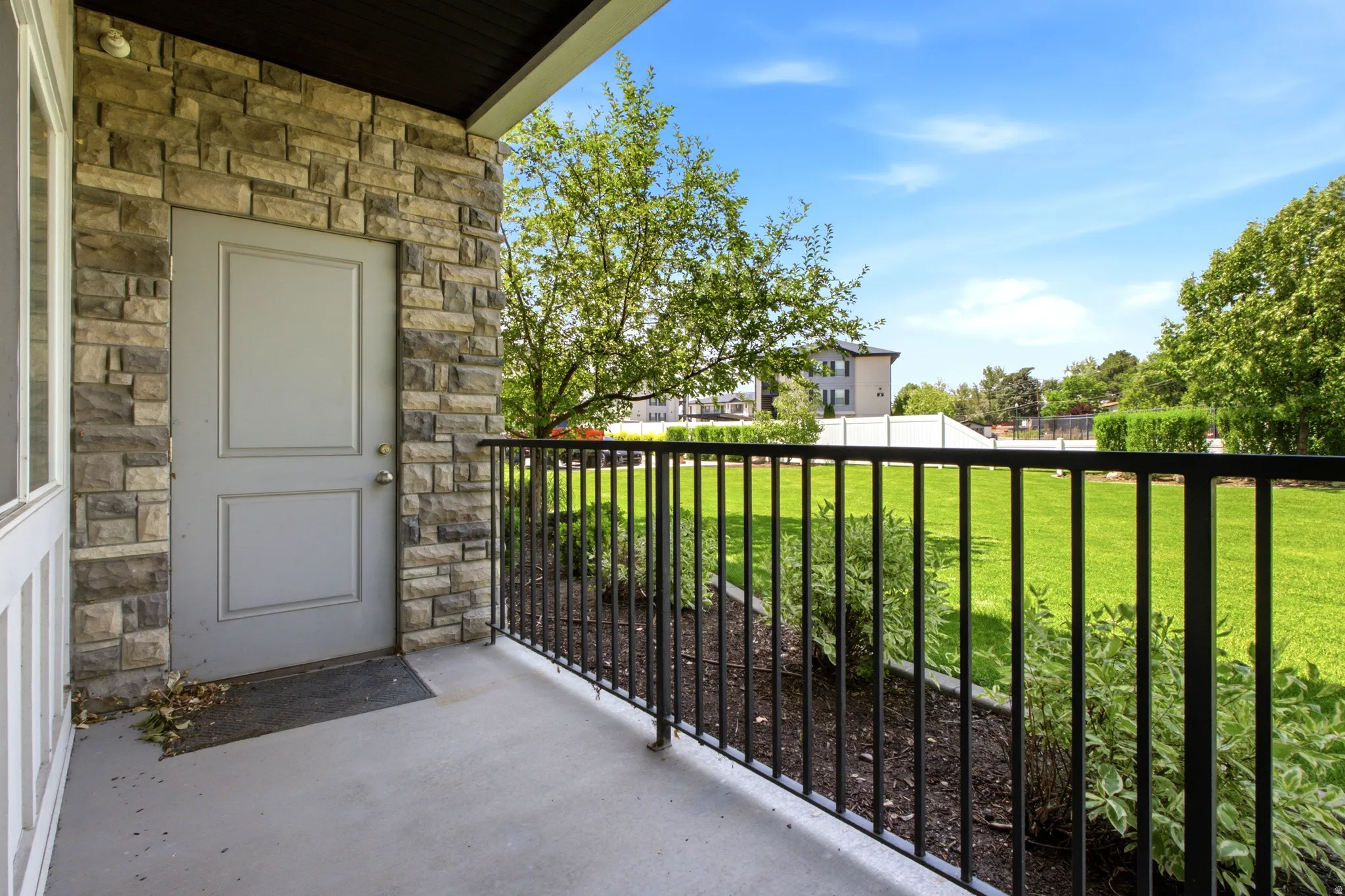 Exterior stone wall with a paneled door and a black metal railing