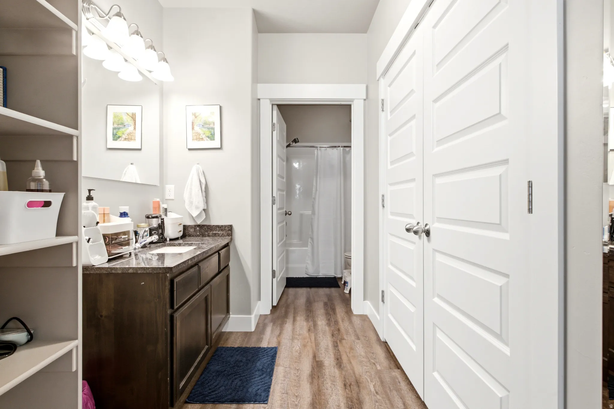 Bathroom featuring a dark wood-finish vanity with a dark countertop, an integrated sink, and a multi-bulb vanity light fixture