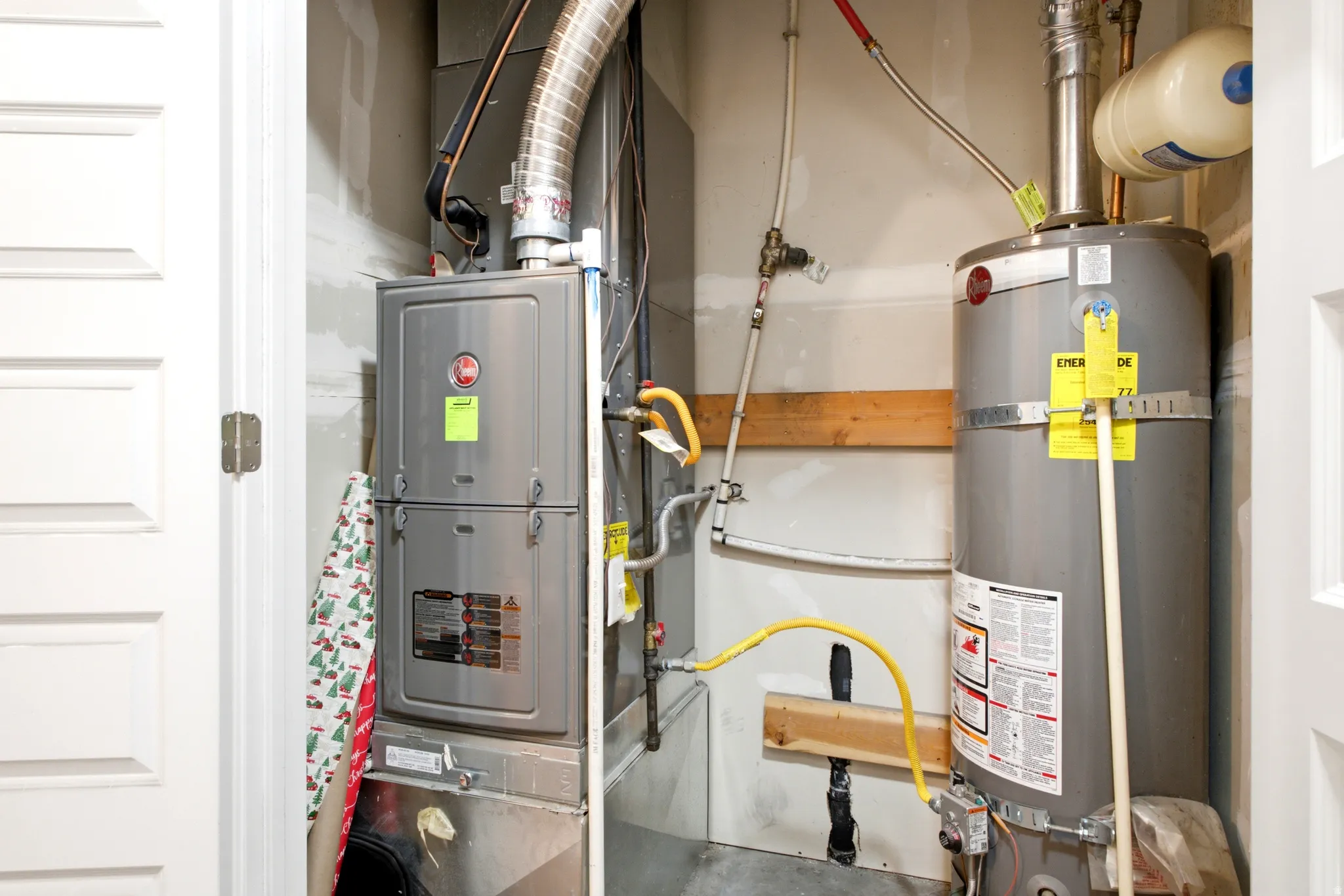 Dedicated utility closet featuring a water heater and furnace with exposed ductwork