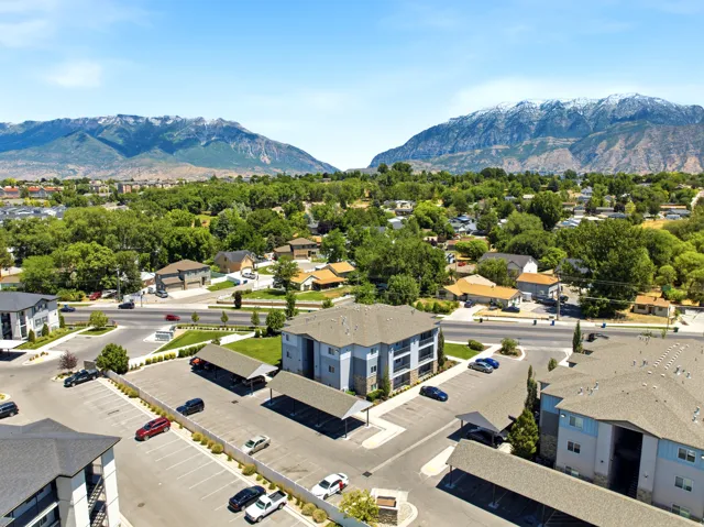 Contemporary apartment buildings featuring covered parking structures, manicured landscaping, and mountain backdrops