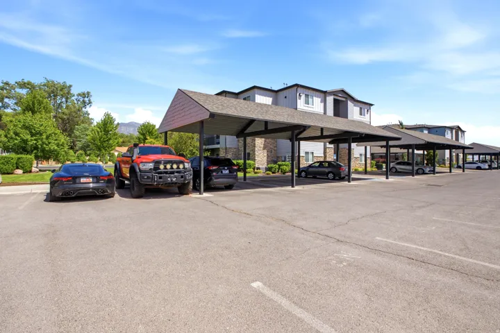 Expansive paved parking lot featuring covered carports with dark roofs