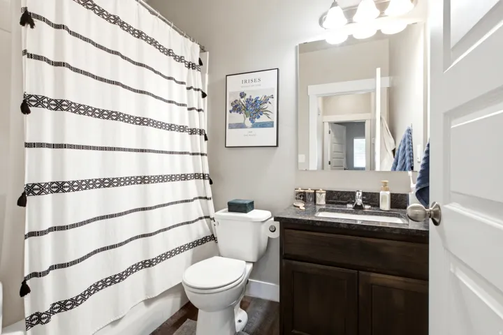 Full bathroom featuring a dark wood-finish vanity with a dark countertop, an undermount sink, and a chrome faucet