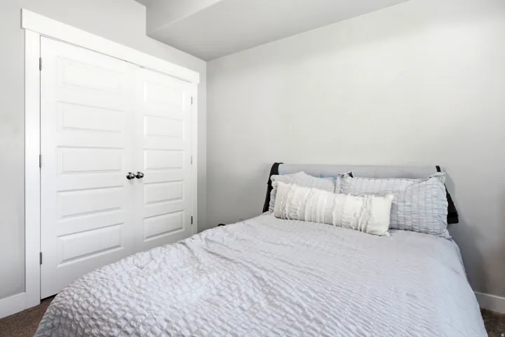 Bedroom featuring light gray wall paint, crisp white trim, and a built-in closet with paneled bifold doors