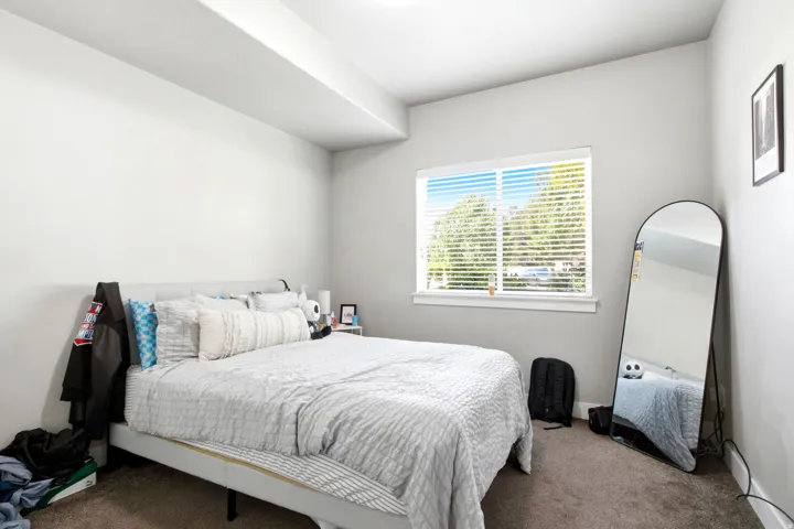 Bedroom featuring neutral-toned walls, a single window with blinds, and dark carpet flooring