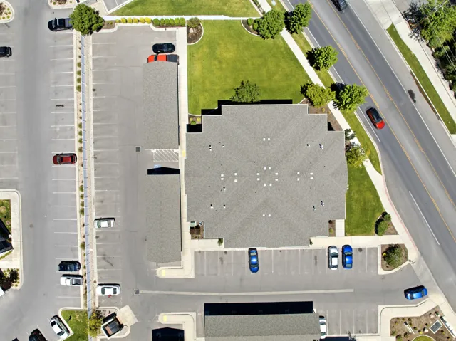 Commercial property featuring a large asphalt parking lot with marked spaces, extensive green lawn areas, and mature landscaping