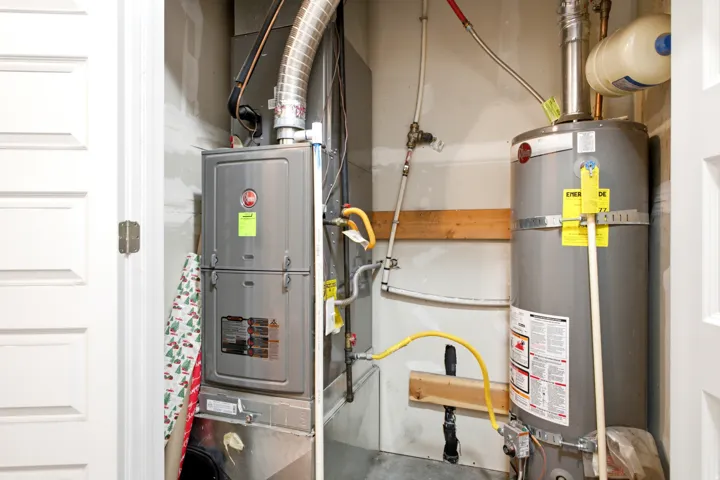 Dedicated utility closet featuring a water heater and furnace with exposed ductwork