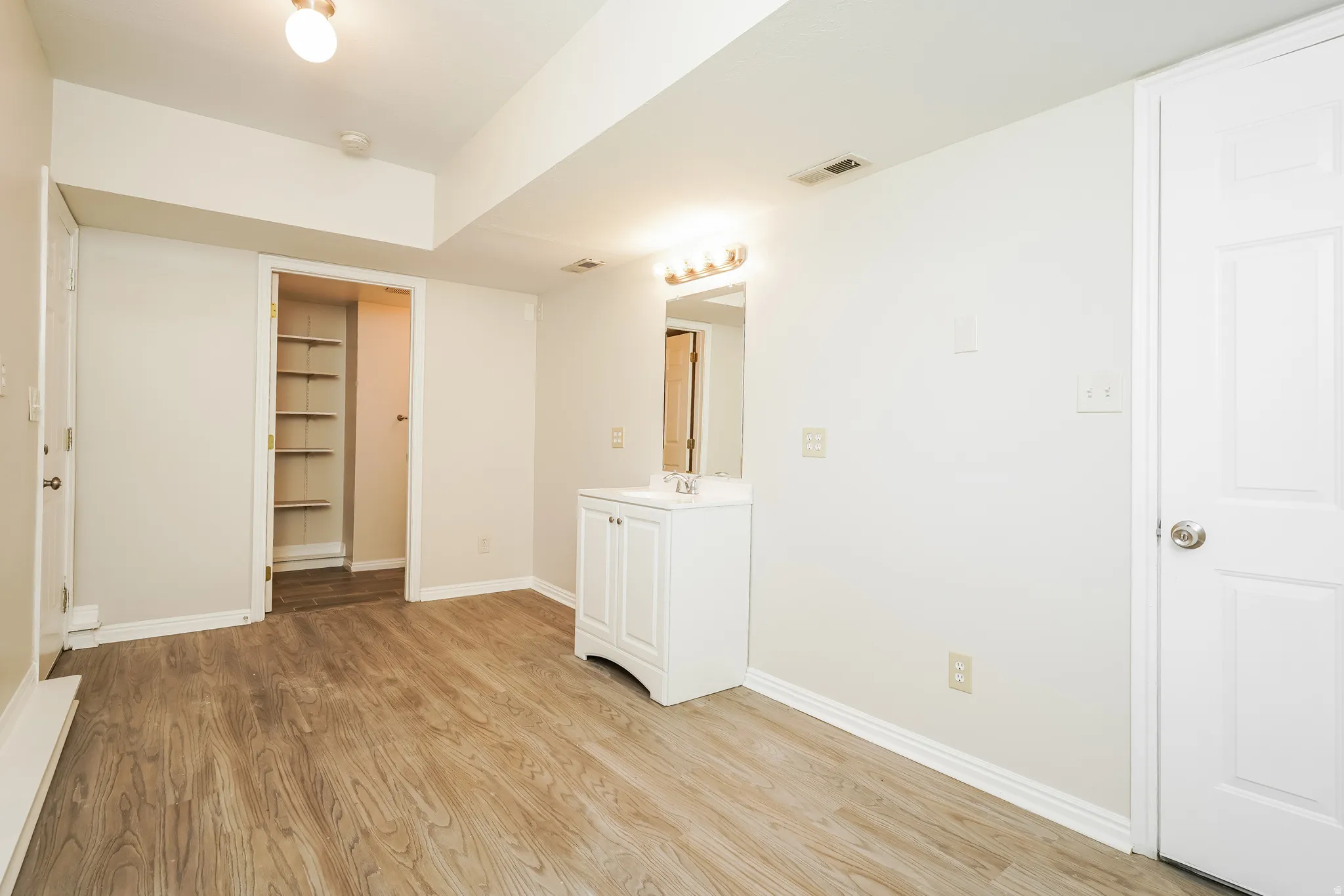 Spacious room featuring wood-finish flooring, light-toned walls, and white trim