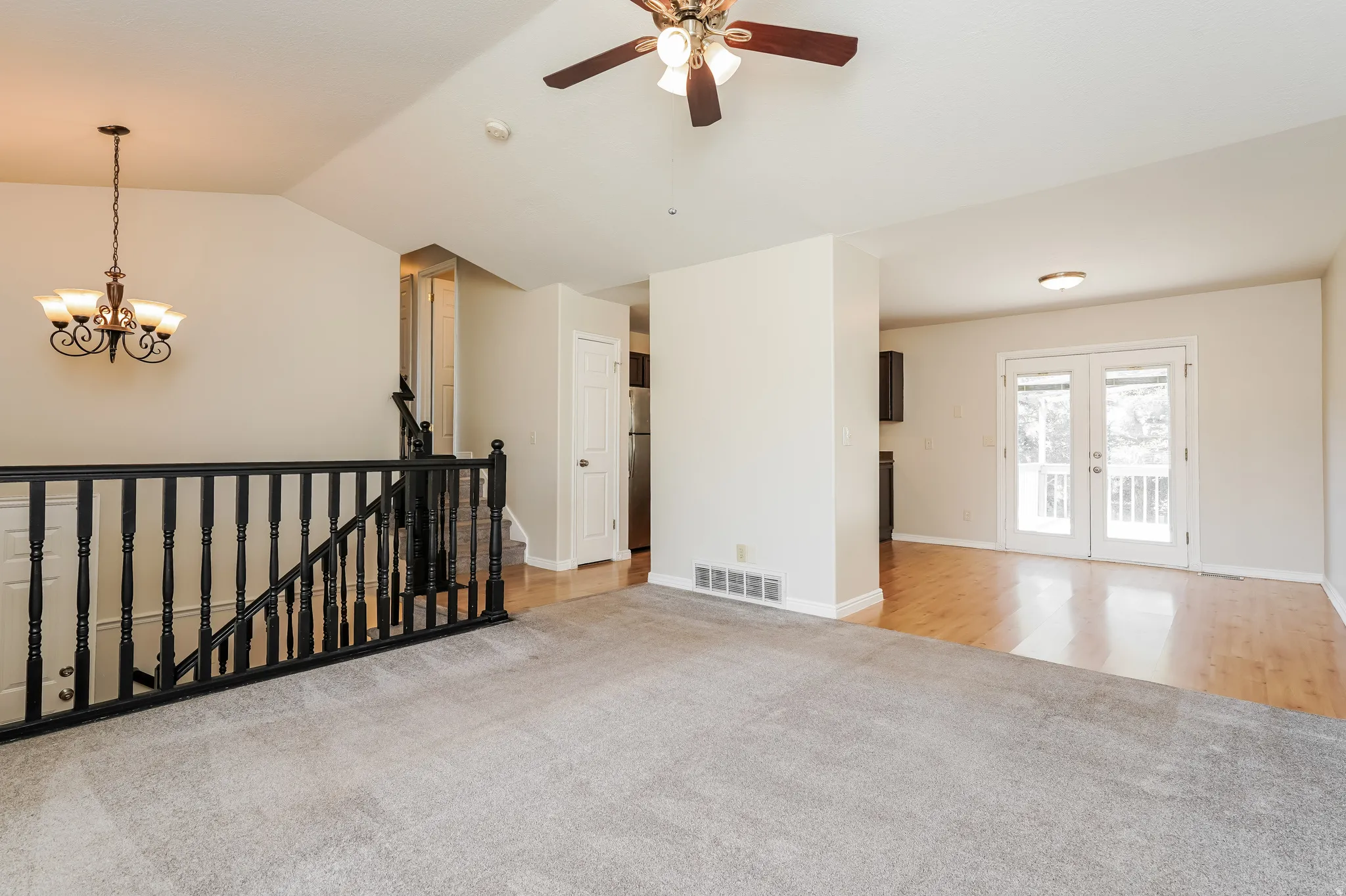 Carpeted living area with a vaulted ceiling and a ceiling fan