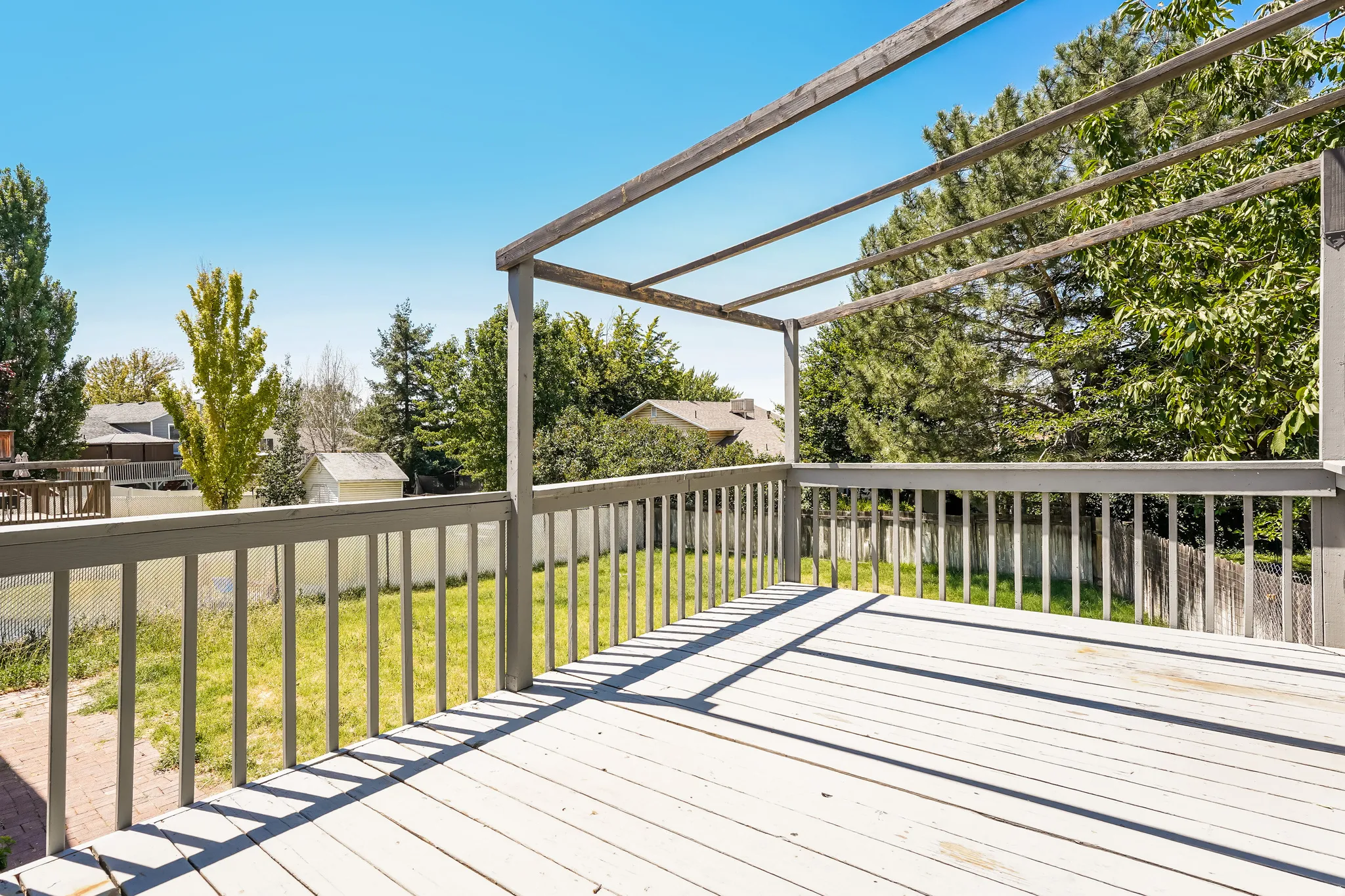 Spacious outdoor deck with a pergola structure, painted wood-finish flooring, and perimeter railing
