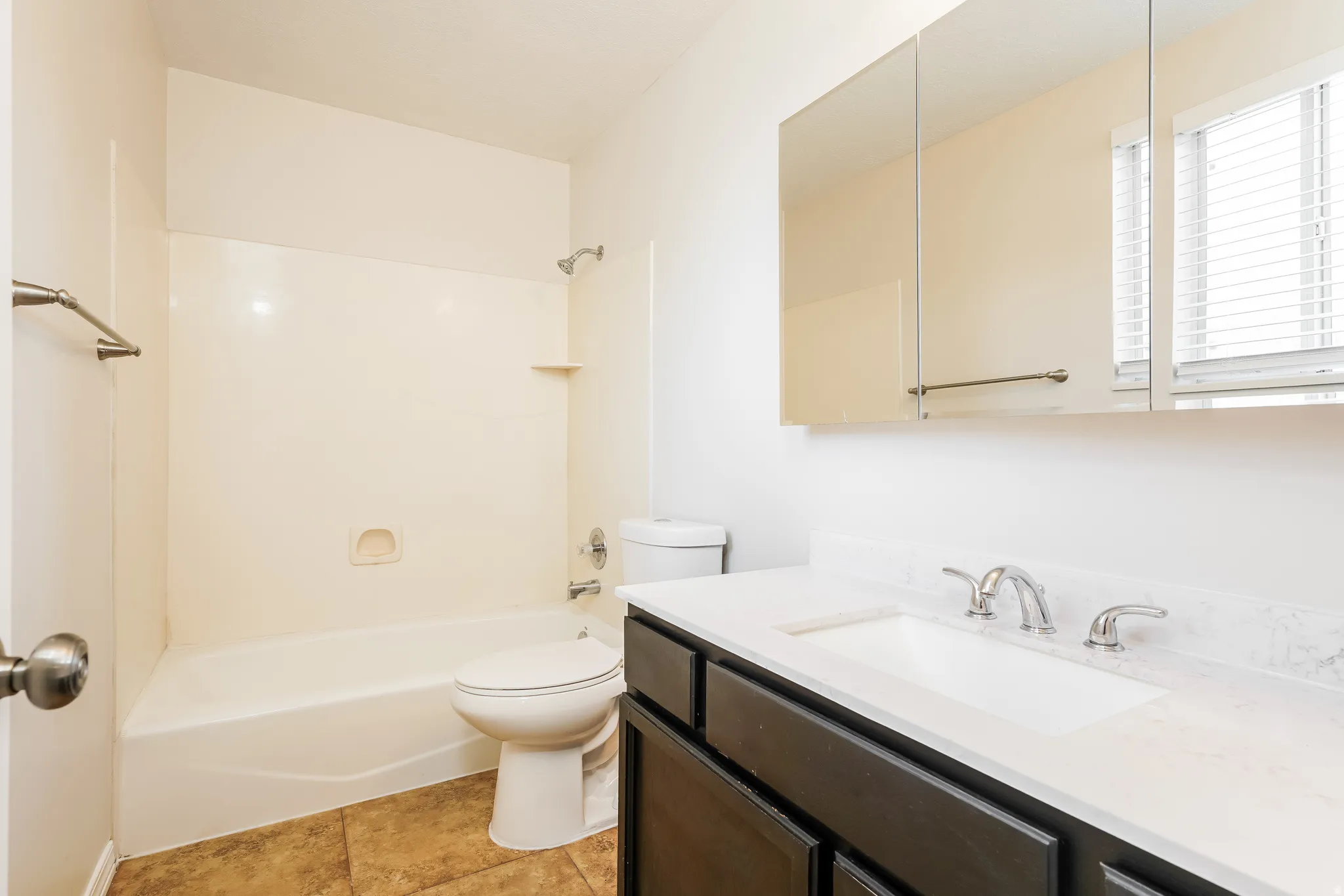 Bathroom featuring a dark wood-finish vanity with a light countertop, integrated sink, and brushed nickel fixtures