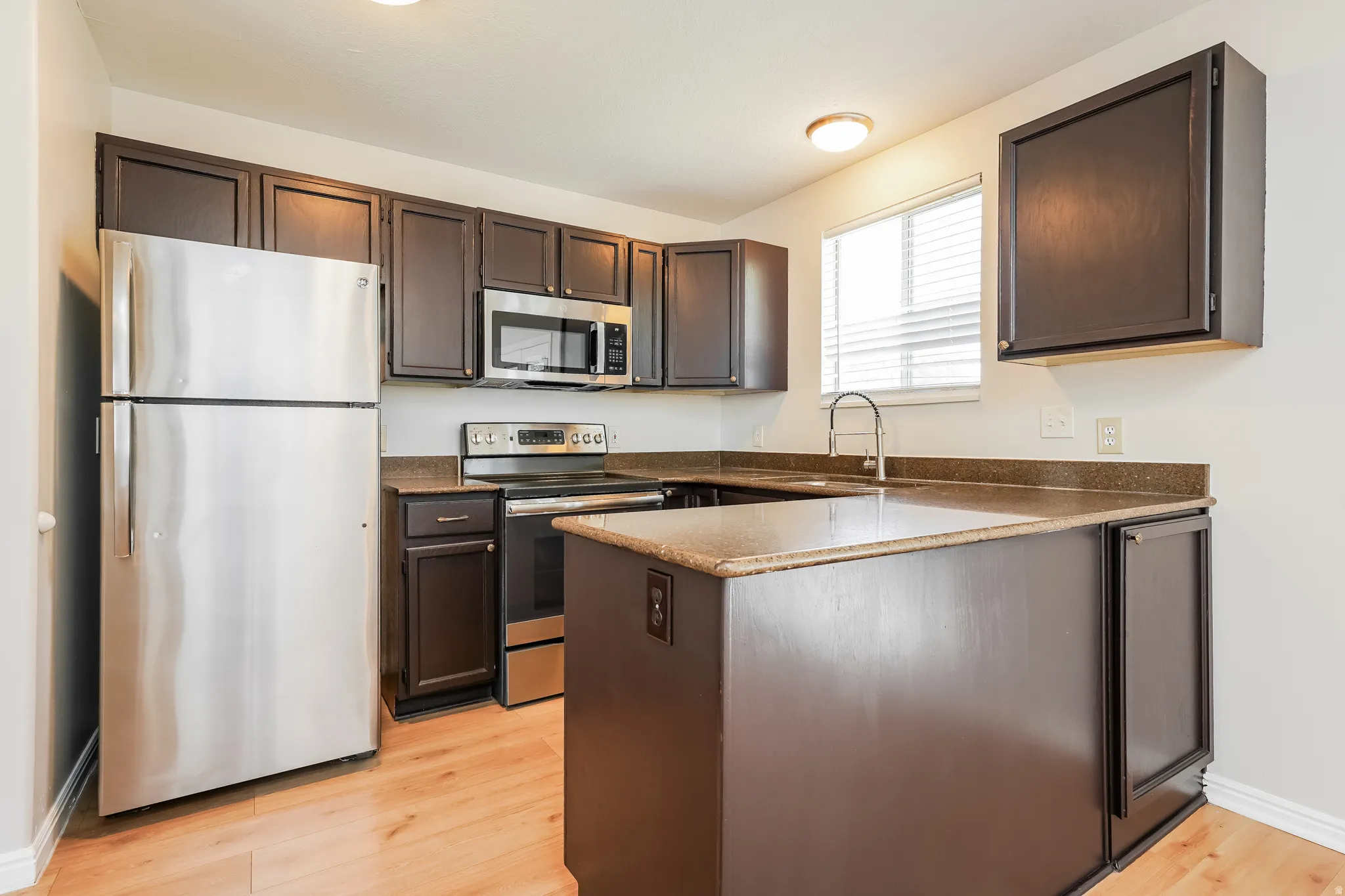 Modern kitchen featuring wood-finish flooring and dark cabinetry