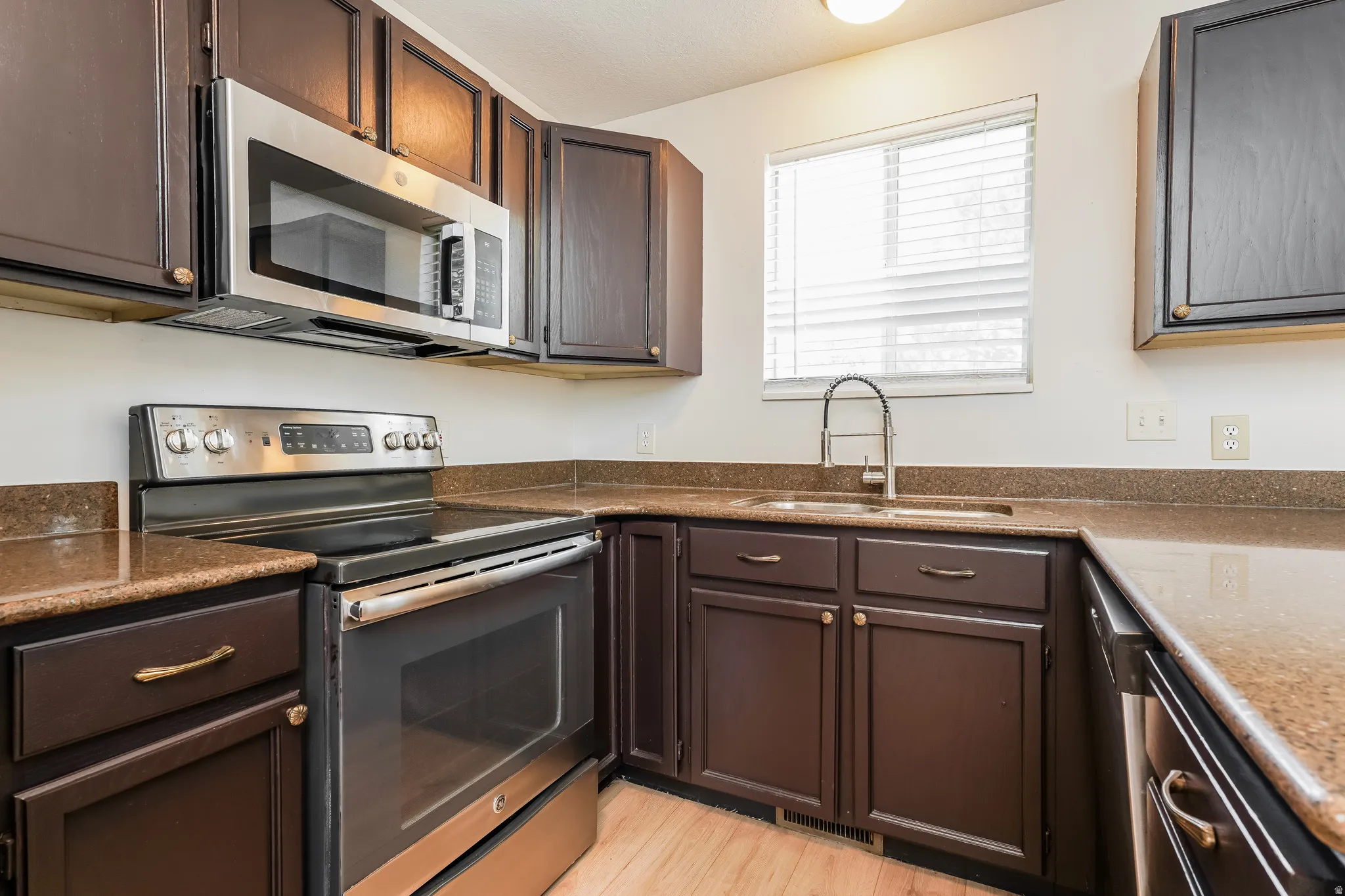 Kitchen featuring dark wood cabinetry, light-toned countertops, and wood-finish flooring