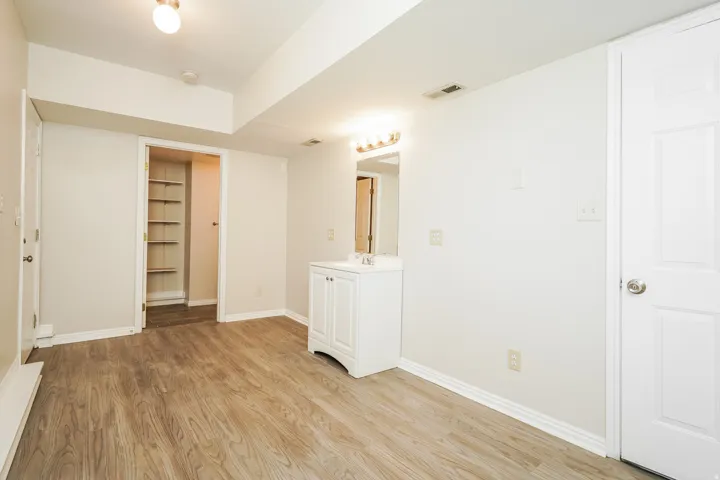 Spacious room featuring wood-finish flooring, light-toned walls, and white trim