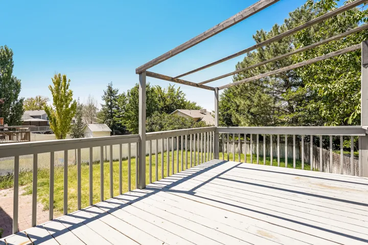 Spacious outdoor deck with a pergola structure, painted wood-finish flooring, and perimeter railing