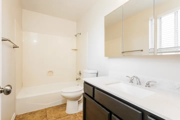 Bathroom featuring a dark wood-finish vanity with a light countertop, integrated sink, and brushed nickel fixtures